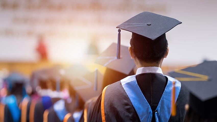 Estudiante con toga y birrete durante ceremonia de graduación, representando los beneficios de un seguro educativo o plan de ahorro familiar con SGroup Seguros y Fianzas.