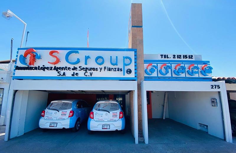 Fachada de la sucursal SGroup Hermosillo con dos vehículos rotulados en el estacionamiento.